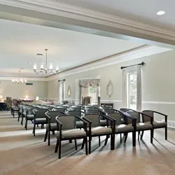 Salle de cérémonie funéraire lumineuse aménagée avec rangées de chaises et lustres classiques