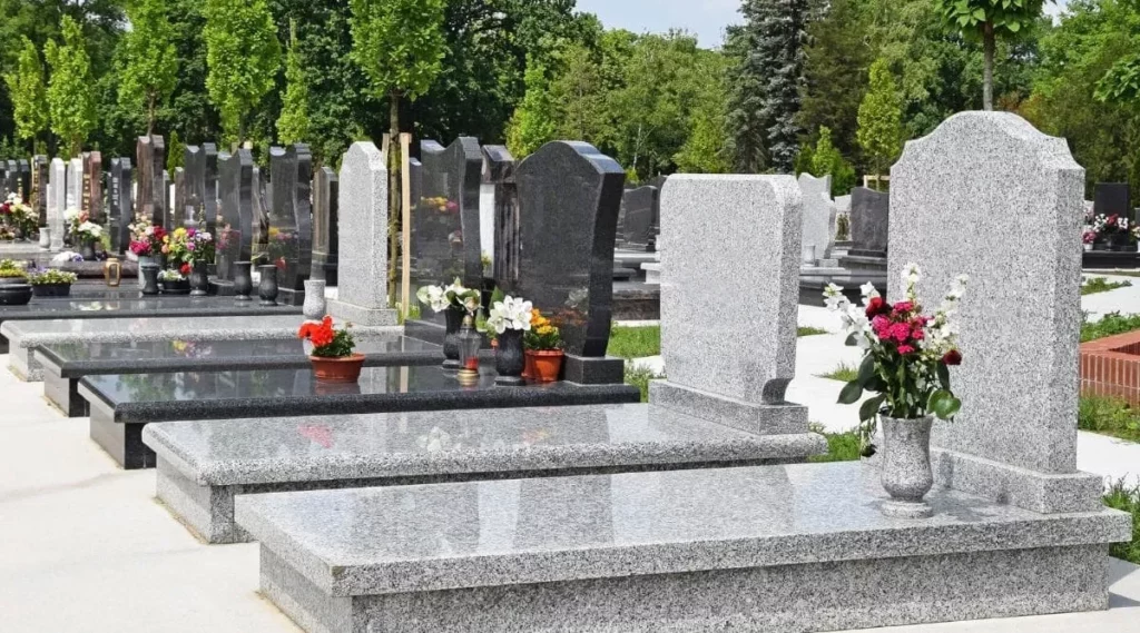 Pierres tombales en granit alignées dans un cimetière paysager