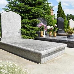 Monument funéraire et pierre tombale en granit clair dans un cimetière