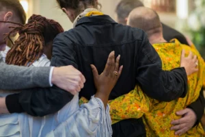 Famille et proches enlacés en signe de solidarité et de recueillement pendant un hommage.